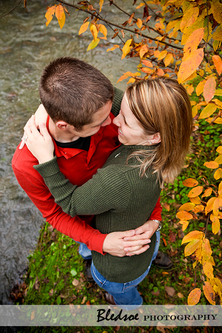 "Engaged couple hugging amidst fall leaves"