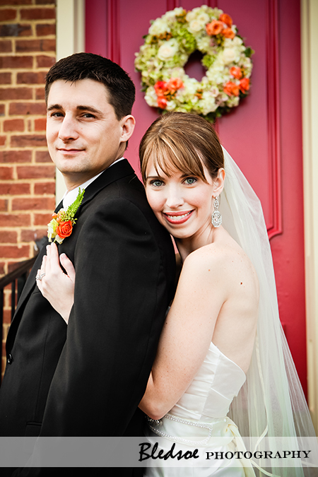 "Bride and groom pose in front of red door"